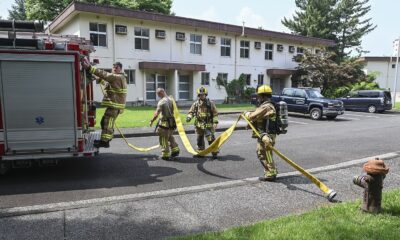 Firefighters in protective gear carrying out a training exercise with hoses in a city training yard.