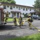 Firefighters in protective gear carrying out a training exercise with hoses in a city training yard.